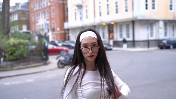 Young woman flips her hair at camera in Soho, London, medium shot slow motion