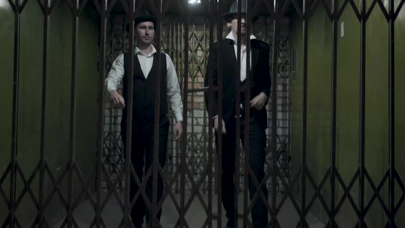 Two Gangsters Men in Formal Suits and Fedora Hat Opening a Metal Forged Gates