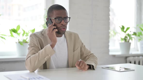 African Man Talking Angrily on Smartphone in Office