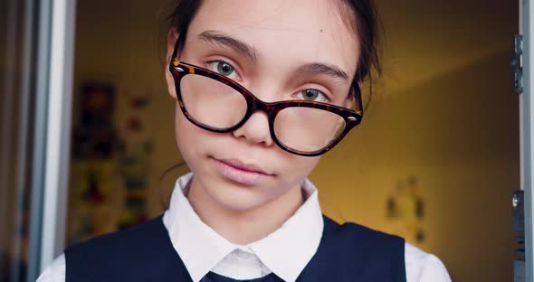 Serious Smart 10 Years Old Schoolgirl Adjusts Her Eyeglasses and Looking at Camera