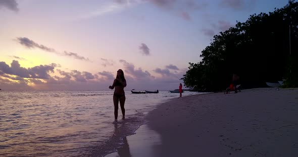 Sexy fun women on photoshoot enjoying life on beach on clean white sand and blue 4K background