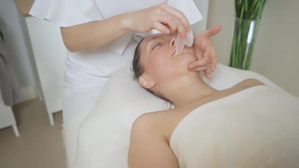 Beautiful Brunette Woman in Spa Salon on Massage with Gouache Stones