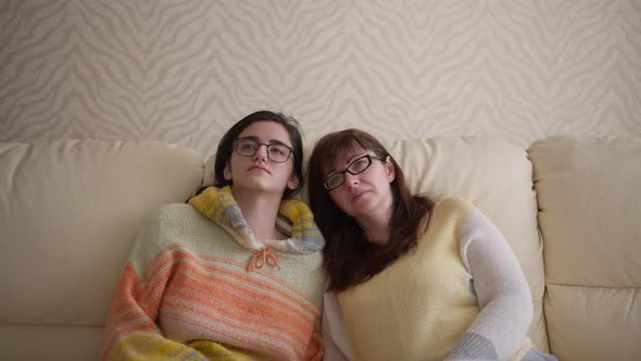 Mom and Daughter Are Sitting on the Sofa and Watching Some Information Watch Tv