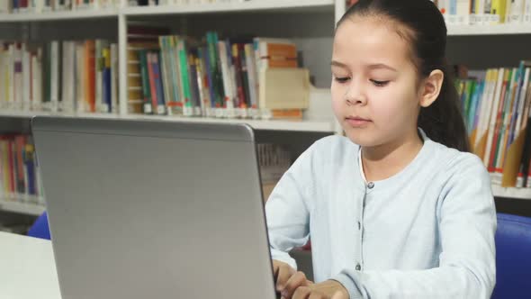 Pretty Little Asian Girl Studying Working on Her Laptop