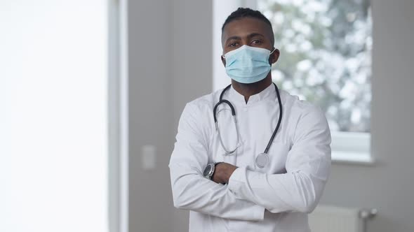 Medium Shot Portrait of Confident African American Man in Medical Uniform and Coronavirus Face Mask