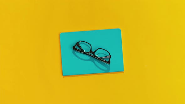 Notepad Glasses Pen and Sanitizer Appear Against an Orange Background