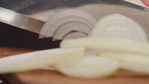 Woman Cuts Onions on a Board in the Evening, Black Background