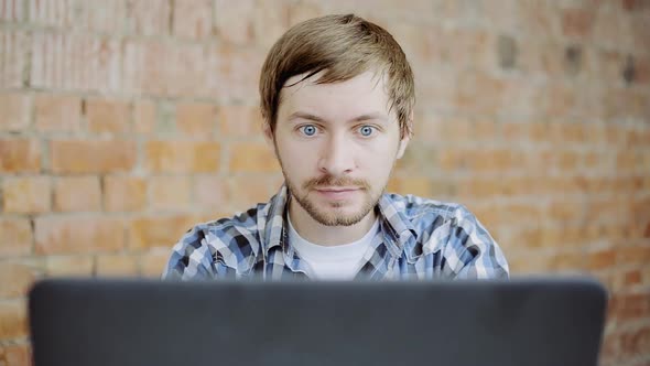 Young man very happy and rejoices sitting in front of laptop