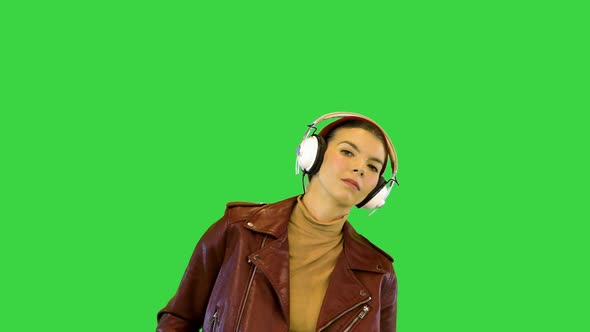 Young Girl in Stylish Clothes Starts to Dance While Listening to Music with Headphones on a Green