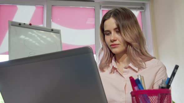 Attractive Female College Student Smiling To the Camera, Working on a Laptop