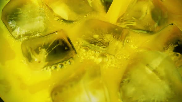 Pouring orange juice into a glass with ice. Slow motion.