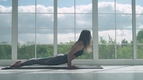 Young Female Performs Stretching and Doing Yoga in a White Room Filled with Light the Girl Performs