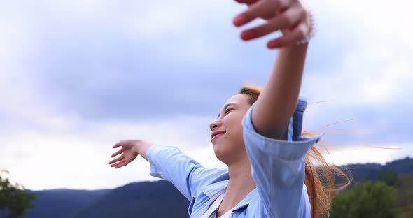 Freedom Asian young woman raising hands on the top at the mountain.