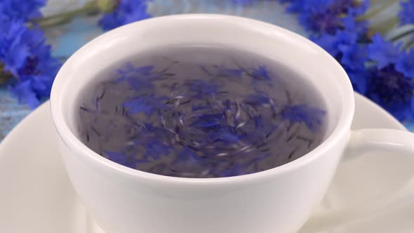 Brewing a tisanes from knapweeds flowers in white cup.