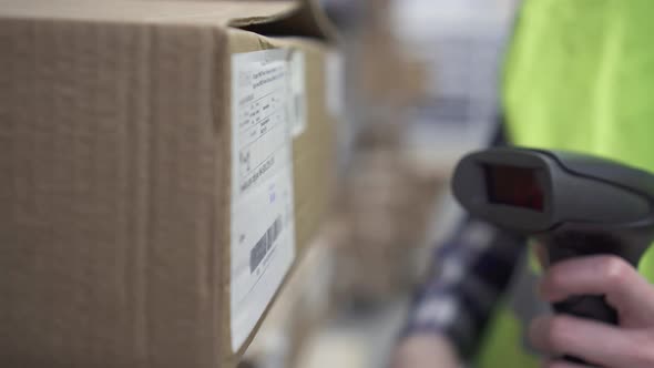 Hand Holds a Barcode Scanner in the Warehouse