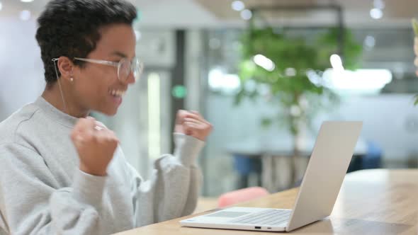 Casual African Woman Celebrating Success on Laptop 