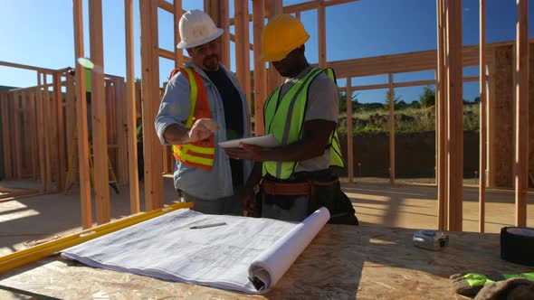 Construction workers using digital tablet on job site alt