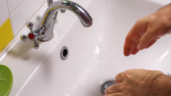 Close-up of a man wiping his hands over the sink with a blue towel after washing them