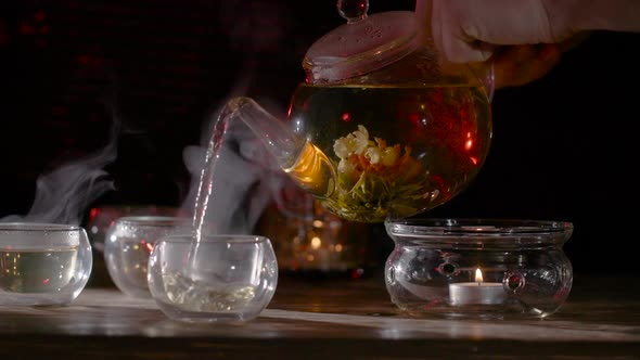 Pouring Fresh Brewed Flower Tea into a Glass Mug.