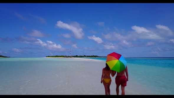 Romantic couple in love on relaxing resort beach vacation by aqua blue ocean with white sand backgro