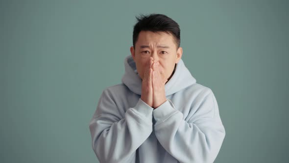 Asian man wearing hoodie getting upset about losing