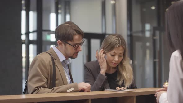 Couple Choosing Hotel Room at Reception