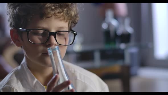 Portrait of Caucasian Boy Holding Flask with Blue Liqud and Thinking. Close-up Face of Intelligent