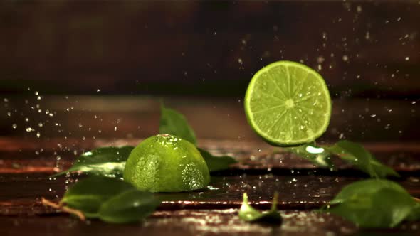 Super Slow Motion Halves of Lime Fall on the Table with Splashes of Water