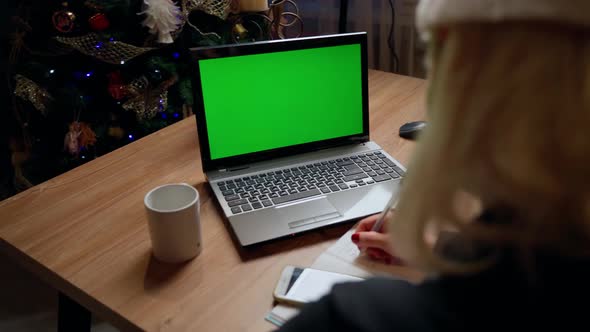 Female person writing and looking at laptop green screen at home indoors at christmas