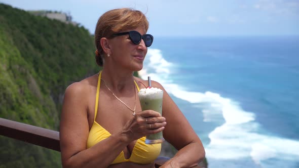 Portrait of Caucasian Middle Aged Woman in a Swimming Suit Watching the Ocean From the Terrace with