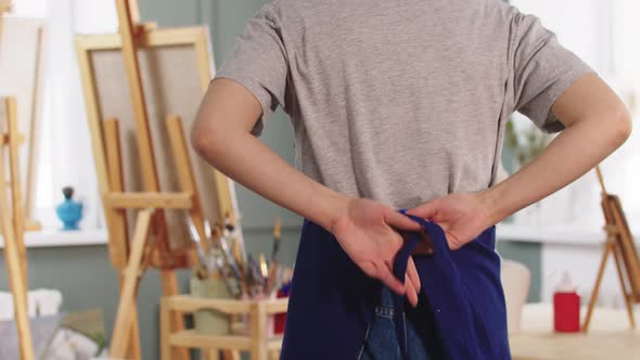 A Woman Artist Enters an Art Studio and Ties an Apron