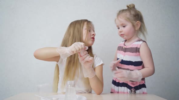Cute Little Girls in Protective Gloves Conduct an Experiments at Home