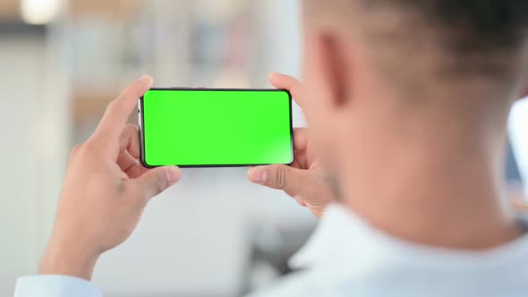 African Man Watching Smartphone with Green Chroma Key Screen