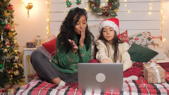 Curly Mother and Daughter Chat Via Video Call Using Laptop