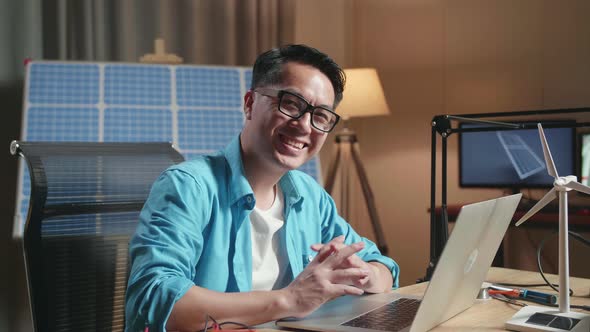 Man Sitting In Front Of Solar Cell Smile To Camera While Working With A Laptop With Wind Power