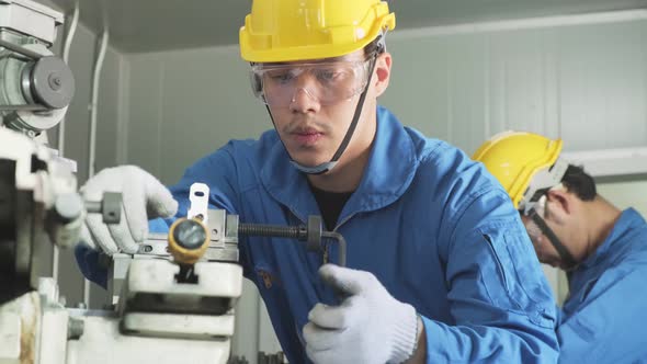 Asian mechanical technicians workers wear protective glasses and hardhat work on milling machine.