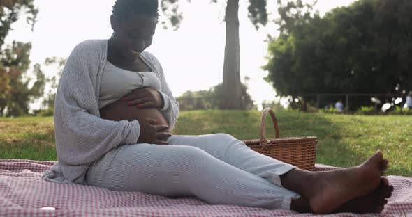 African pregnant woman holding her belly outdoor