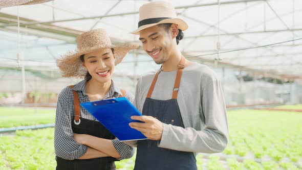 Asian farmers couple work in vegetables hydroponic farm with happiness.