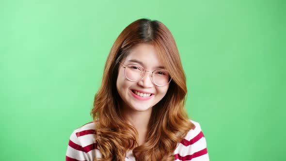 Happy young Asian woman in striped t-shirt wearing eyeglasses looking at camera and smiling joyfully