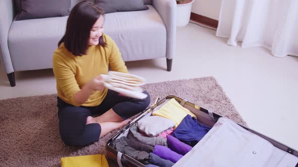 Young woman preparation suitcase getting ready for road trip preparing luggage for vacation. Travel