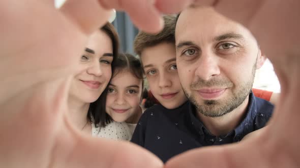 Close Up Portrait of Happy Young Family Making Heart Gesture with Fingers The Family is Resting