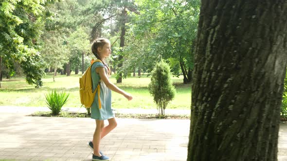 Kid Elementary School Student Walks Through the Park to School in the Morning