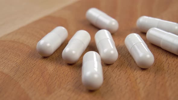 White medical capsules on a wooden surface. Macro