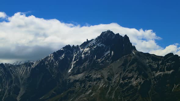 Timelapse Clouds Swirl Over a Mountain Valley a Snowy Peak in the Distance