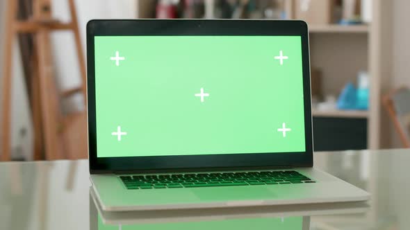 Parallax Shot of a Laptop with Green Screen on and People on the Background