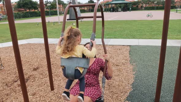Mother and Daughter Playing on an Expression Swing at Playground