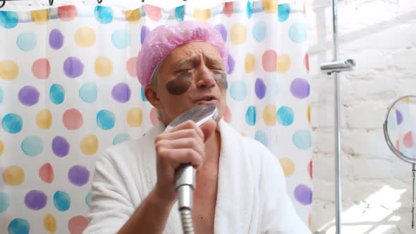 Portrait of Senior Man with Eye Pads Wearing Shower Cap Singing in Bathroom