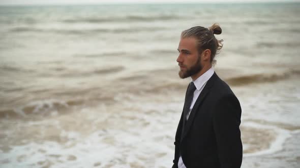 Businesslike Guy in Black Suit and Tie Looking Around Examining Place at Seashore Slow Motion