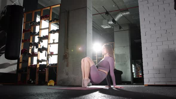 Young Woman Doing Pilates Exercises  Warming Up Her Toes Sitting on the Yoga Mat