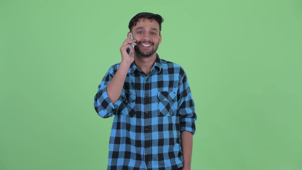 Happy Young Bearded Persian Hipster Man Talking on the Phone